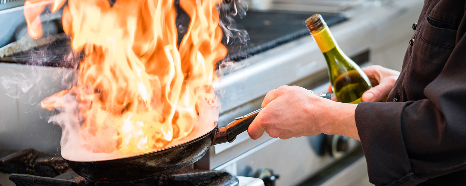 Services header image, chef cooking with flaming skillet